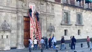 Electricistas tiran la valla de Palacio Nacional y cuelgan una pancarta